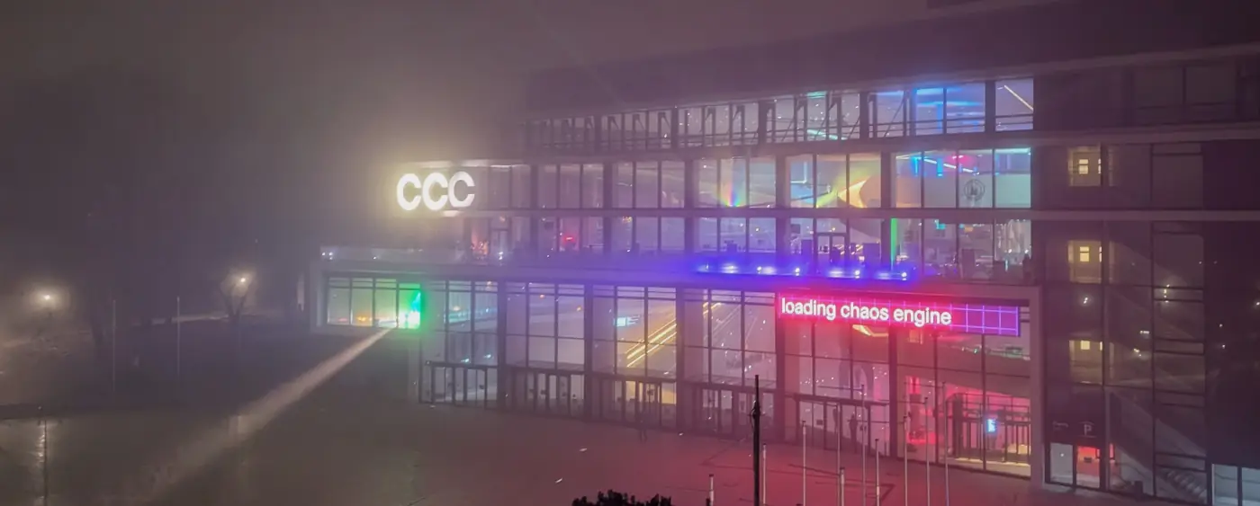 Eingang vom CCH mit Spotlights, die teilweise nach außen leuchten. Auf dem Besucherinformationsdisplay steht "Loading Chaos Engine"
